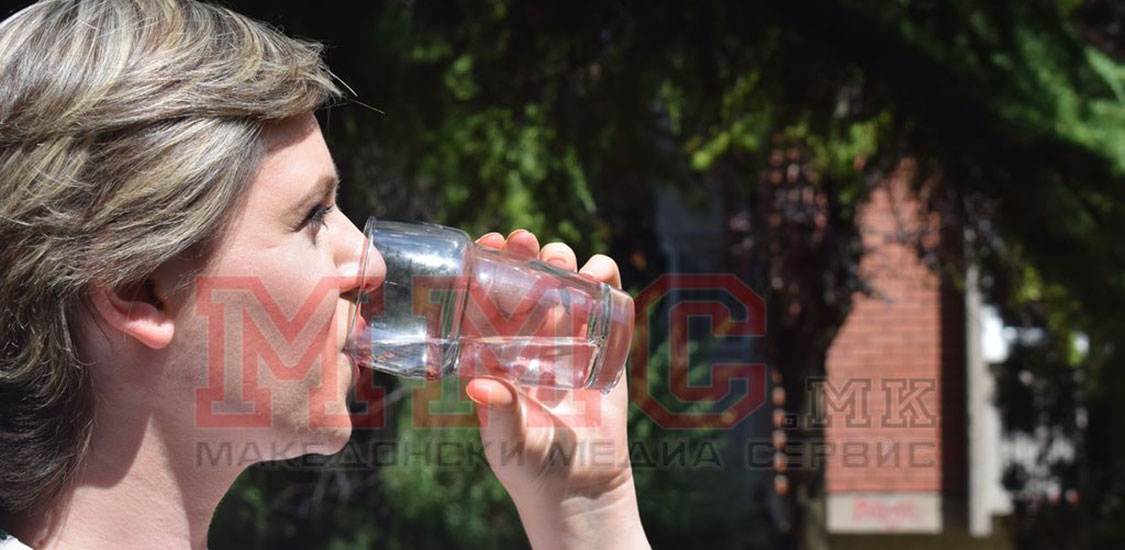 Девојка пие чаша вода.